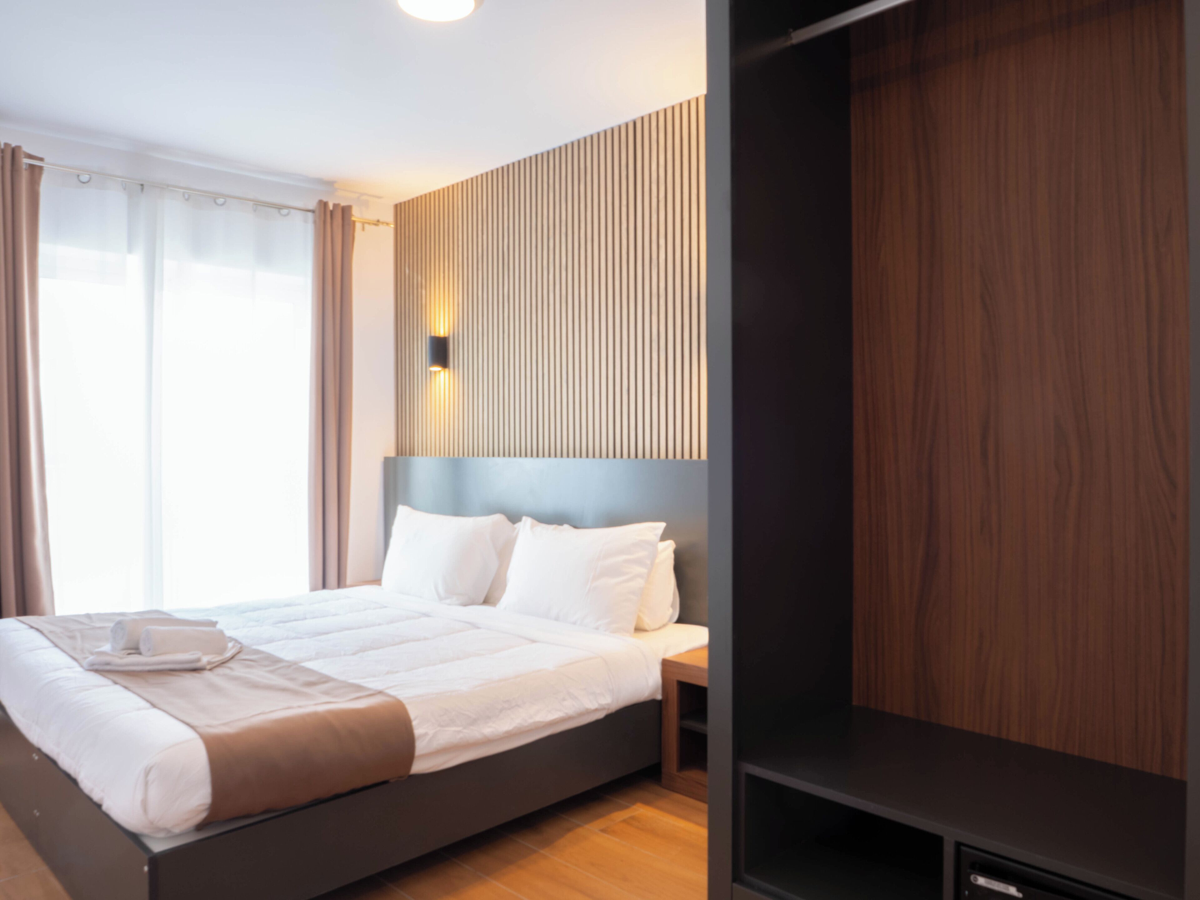 Ein modernes Hotelzimmer mit einem großen Bett, einem Nachttisch und einem Einbauschrank.