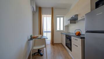 Una cocina compacta con comedor, refrigerador y ventana con cortinas.