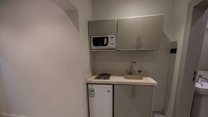 Uma cozinha compacta com micro-ondas, um pequeno frigorífico e uma pia.