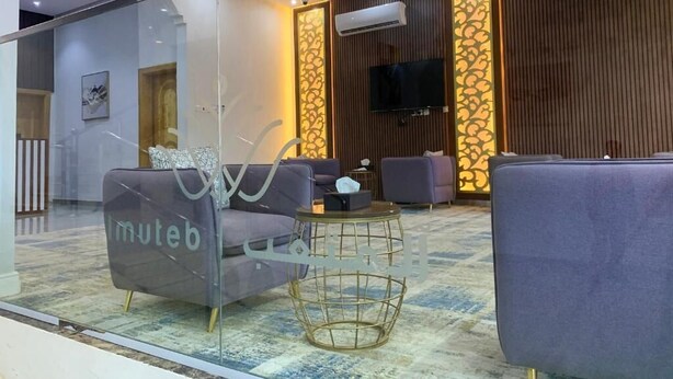 Um saguão moderno com áreas de estar, televisão e painéis decorativos.