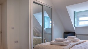 Un dormitorio con una cama grande, un ventanal corredero, un radiador y una ventana con persianas.