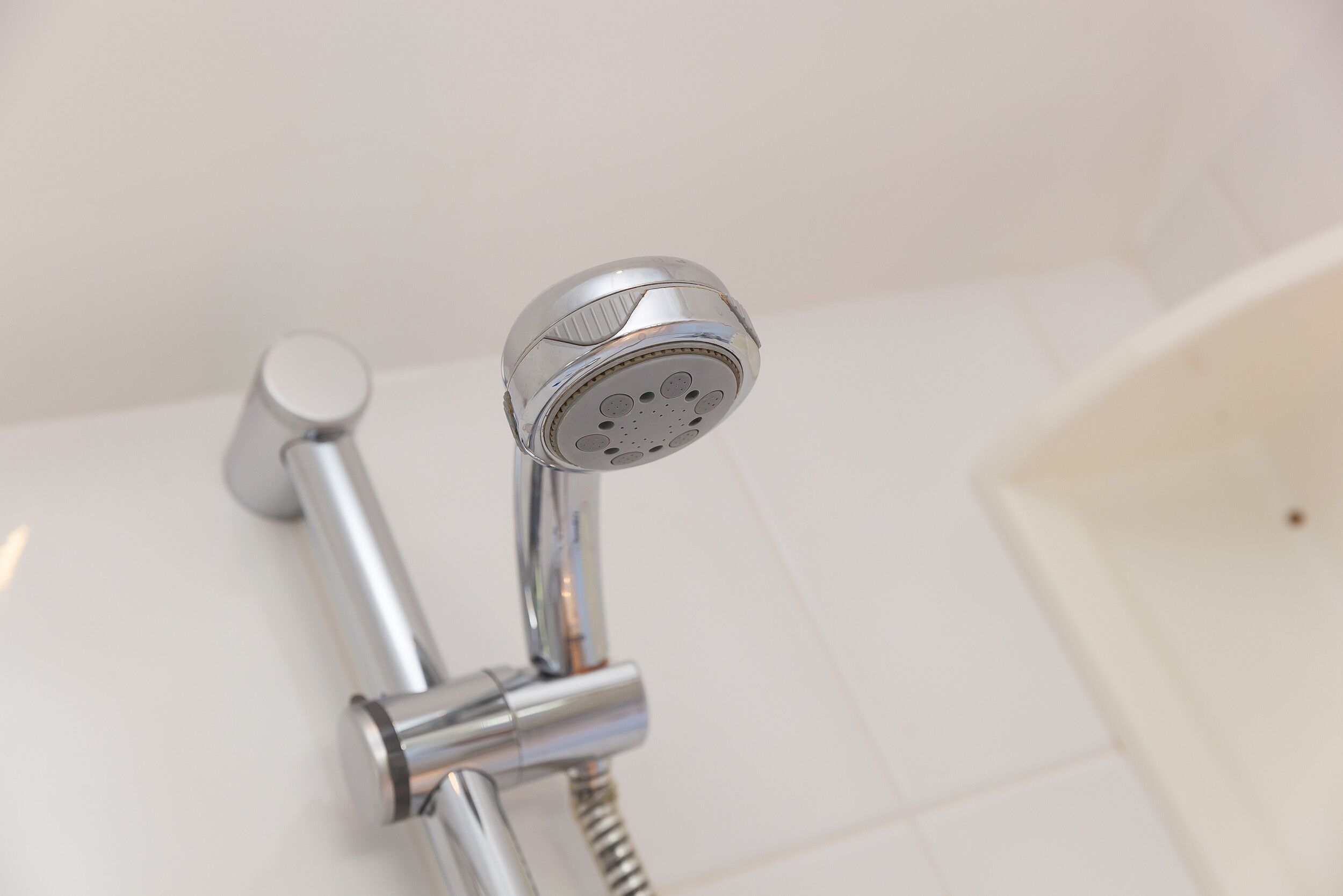 Een moderne douchekop met een gebogen ontwerp, bevestigd aan een chroomfitting.
