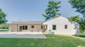 Einbungalow mit überdachter Terrasse, einer kleinen Garage und einem gepflegten Rasen.