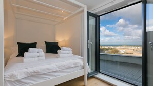 A bedroom with a bed, pillows, and a view through a glass door to the outside. - Beach View (St Ives)