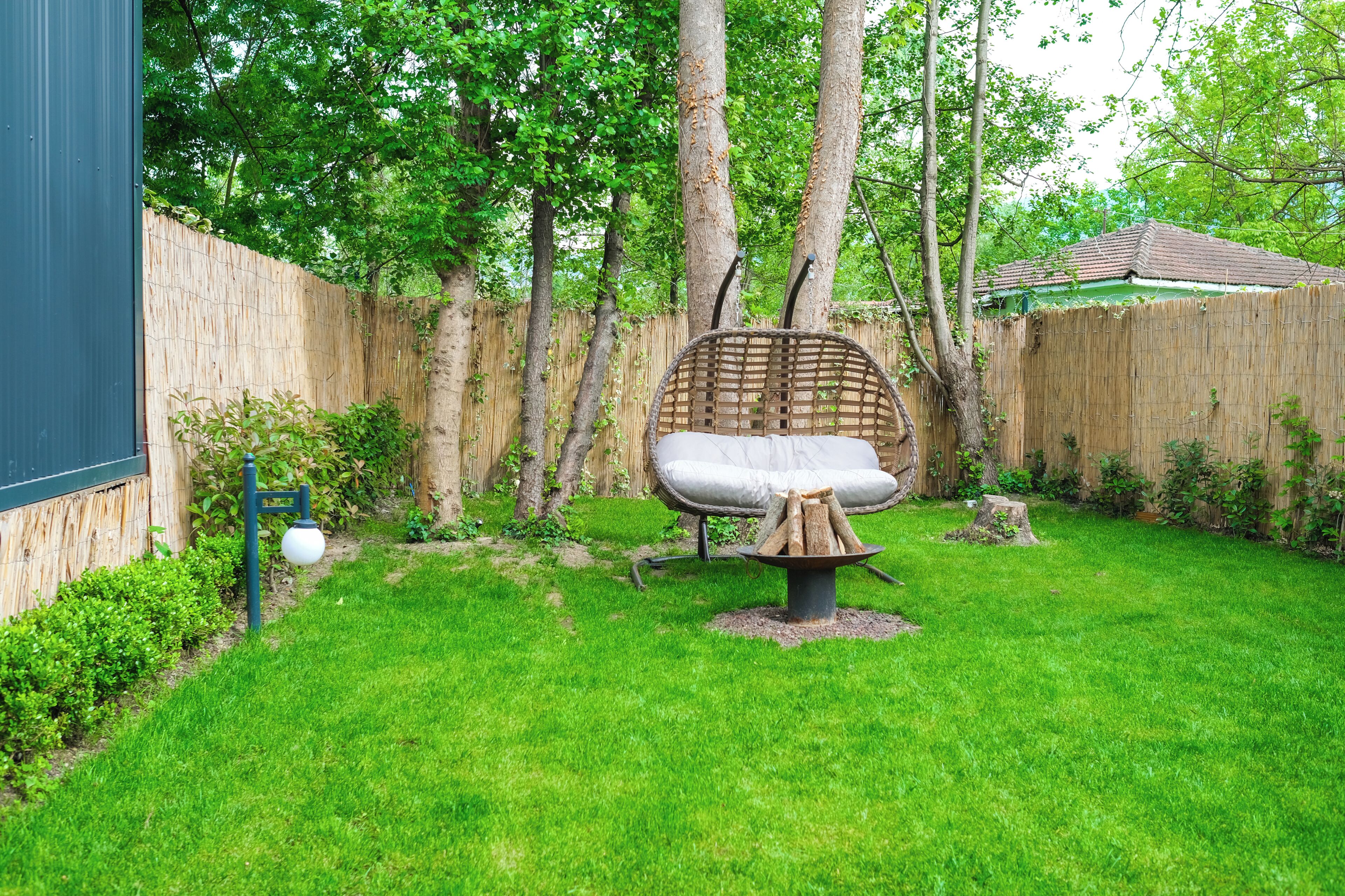 A backyard with a wicker chair, a fire pit, and a wooden fence.