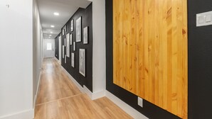 A hallway with wooden flooring, black walls, and framed pictures on the left side. - Listen Linda, 5 Bedroom Home Near Bishop Arts (Dallas)