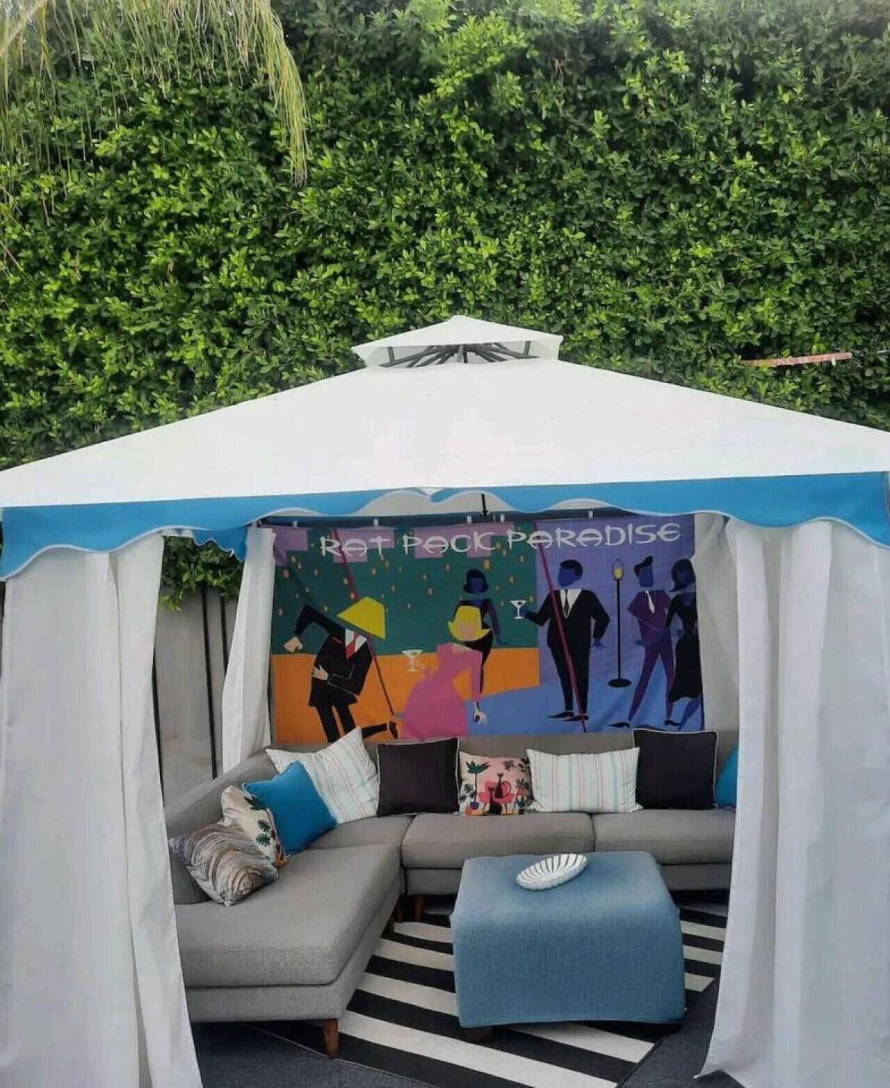 A tent with a colorful mural, a grey sofa with cushions, and a striped rug.
