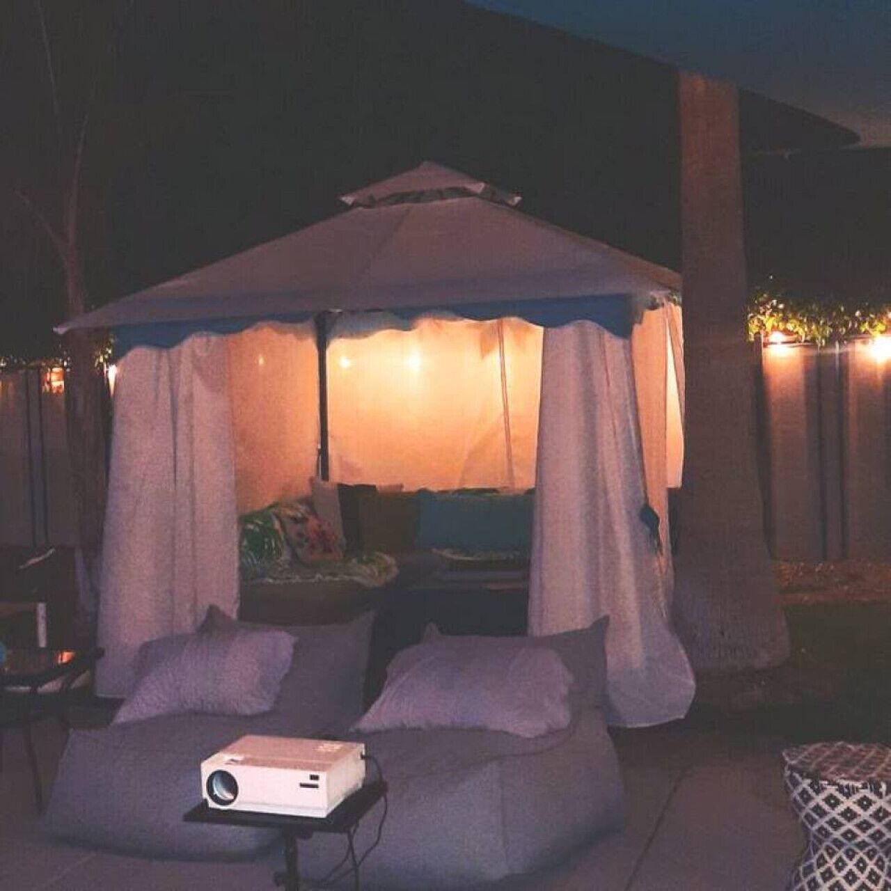 An outdoor seating area with a canopy, a projector, and a table.