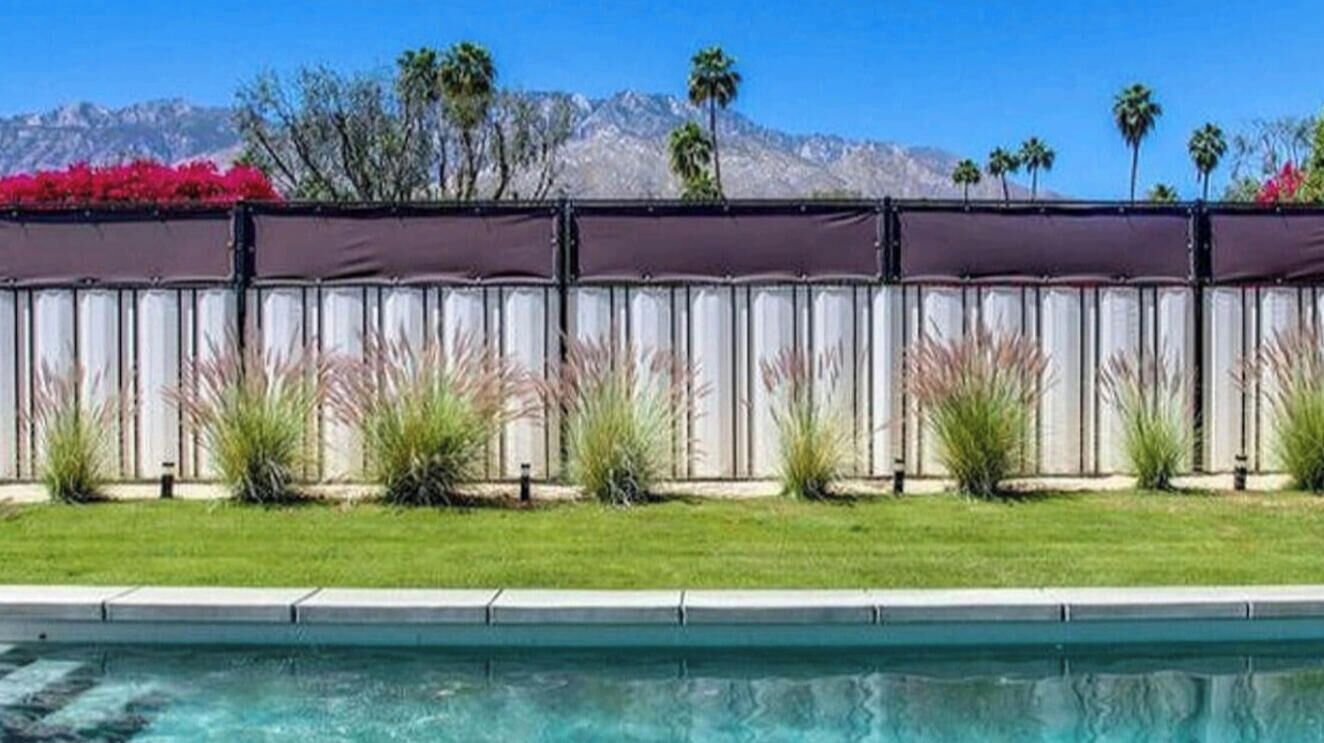 Une piscine avec vue sur les montagnes et bordée d’une rangée de plantes.