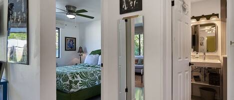 A bedroom with a bed, a ceiling fan, and a window.
