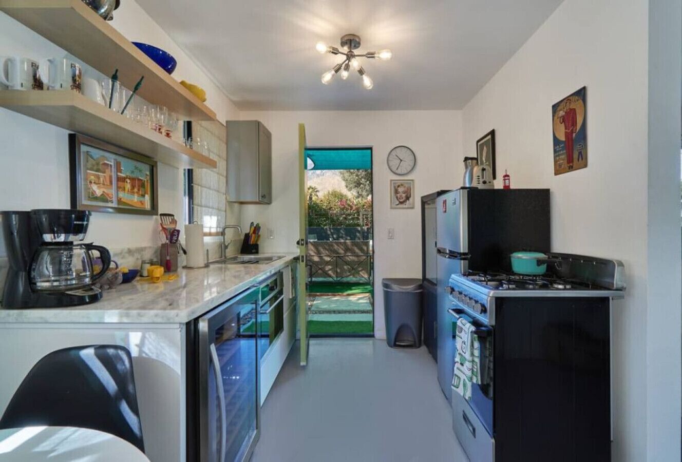 Una cocina compacta con cafetera, estufa y un cubo de basura.