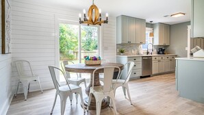 Una cocina moderna con armarios blancos, una mesa redonda de madera y sillas blancas.