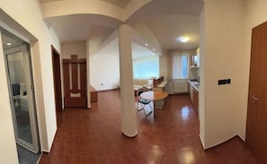 Relax in this open-plan living area with a high ceiling, featuring a dining space and kitchenette.