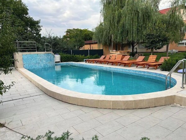 Relax by the pool surrounded by lush vegetation and comfortable lounge chairs.