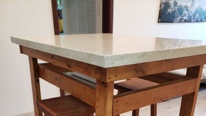 Una mesa de madera con cubierta de mármol y dos taburetes a juego.