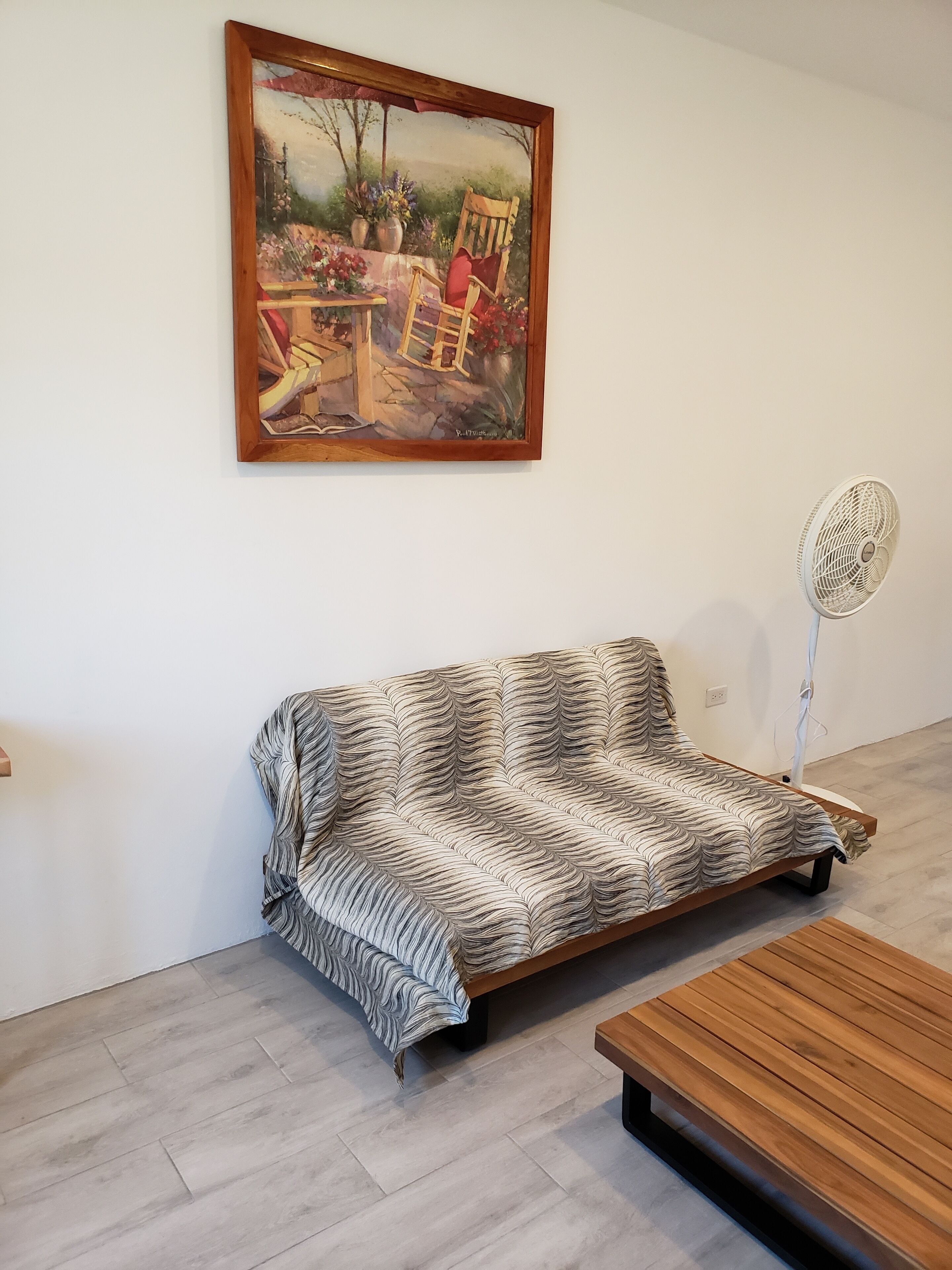 Ein Zimmer mit einer Couch, einem Holztisch und einem Gemälde an der Wand.