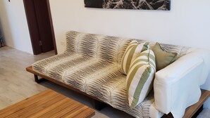 Una sala de estar moderna con un sofá, un banco de madera y un cuadro colgado en la pared.