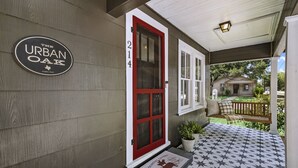 Une entrée de maison avec une porte rouge, un porche doté d’un sol orné d’un motif en étoile et une enseigne indiquant « The Urban Oak ».
