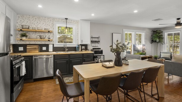Une cuisine moderne avec des meubles en bois, un îlot central et un coin repas comprenant une table et des chaises.
