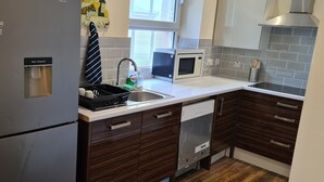 A modern kitchen with a stainless steel refrigerator, a built-in microwave, and a dishwasher. - Florence House , Denbigh (Denbigh)