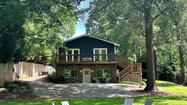 A two-story house with a stone facade, a wooden deck, and a fire pit in the front yard. - The Cottage in the Cove (Denver)