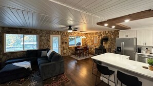 A modern kitchen with a stone wall, wooden ceiling, and a large island with bar stools. - The Cottage in the Cove (Denver)
