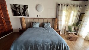 Ein Schlafzimmer mit einem großen Bett, einem hölzernen Kopfteil, einer Wandleuchte und einem Blumentopf.