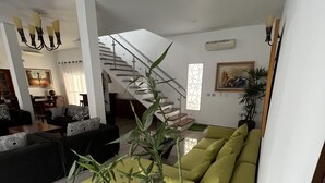Ein modernes Wohnzimmer mit Treppe, einer Sofagarnitur und einer großen Bambuspflanze.