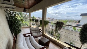 Ein Balkon mit Holzboden, gepolsterten Sitzmöglichkeiten und Topfpflanzen.