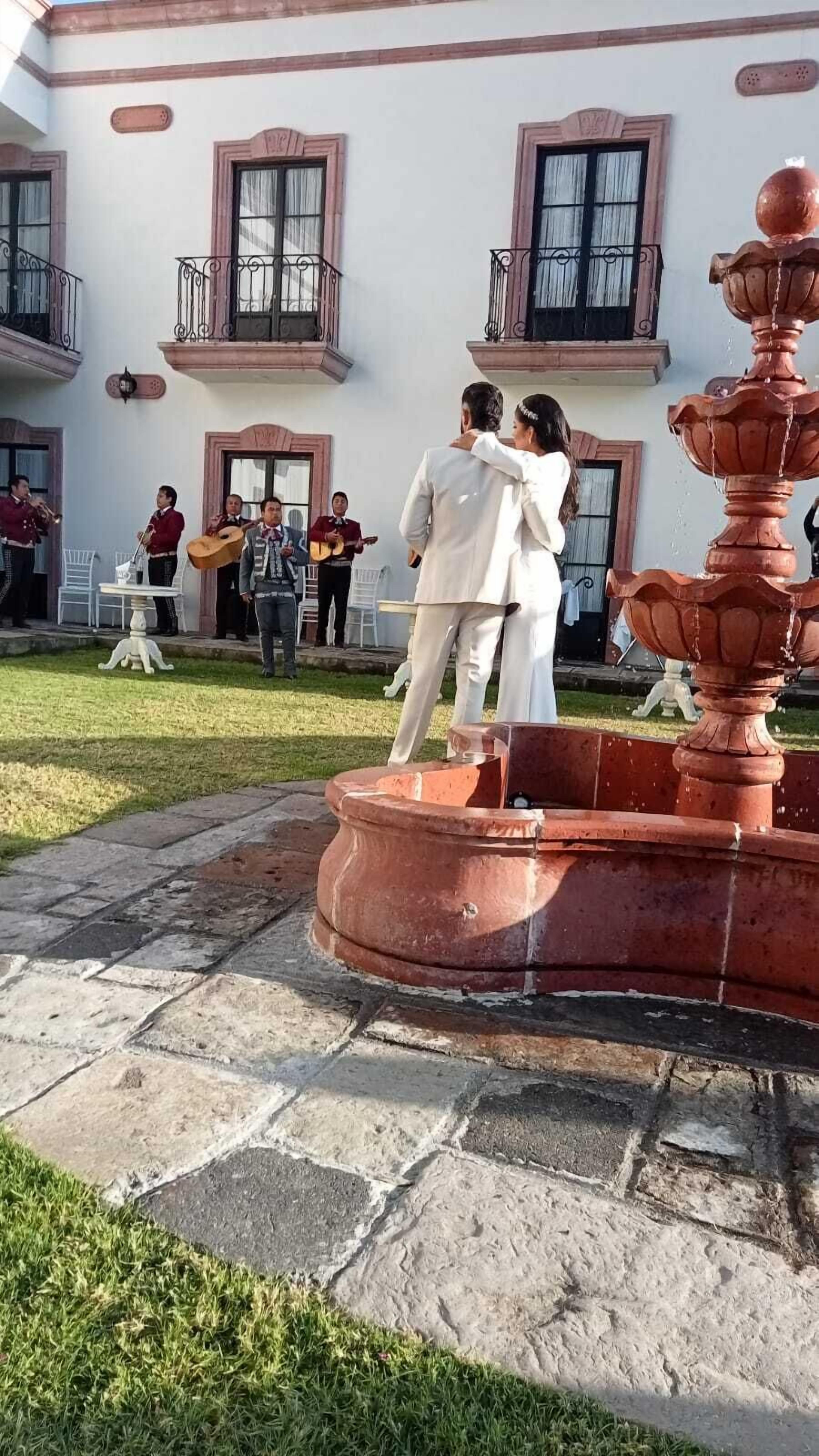 Une cour avec une fontaine, un bâtiment doté de balcons et un groupe de personnes.