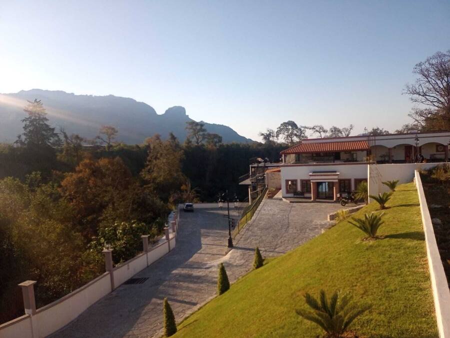 A hotel with a paved driveway leading to a building with a red-tiled roof.