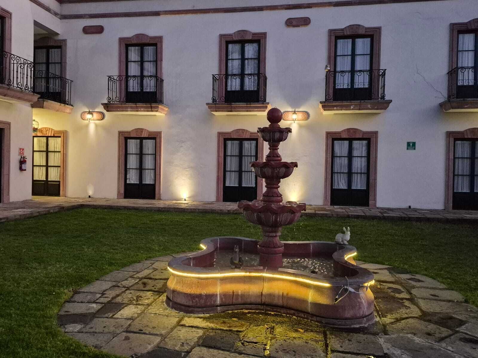 A courtyard with a central fountain, surrounded by a building with multiple balconies and windows.