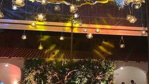 An outdoor dining area with a wooden table and chairs, surrounded by lush greenery and decorative hanging lights. - Hotel Danini (Teziutlan)