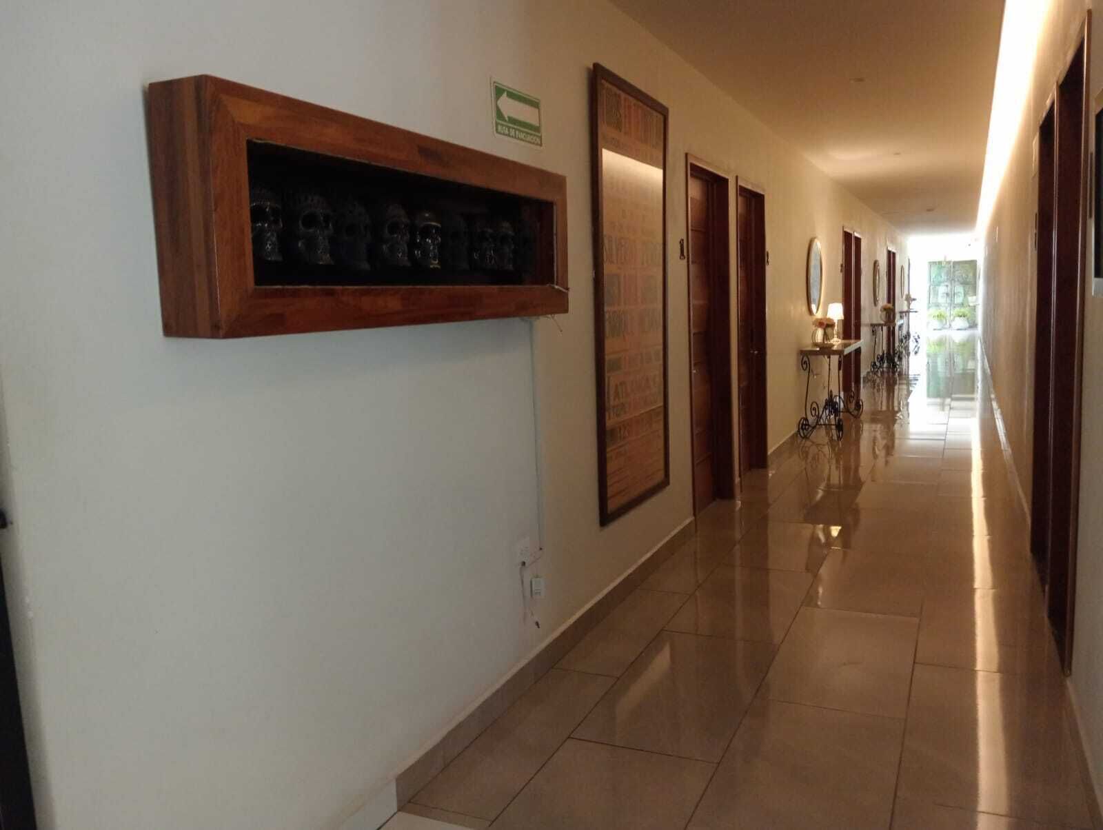 A hotel hallway with a polished tile floor, wooden doors, and a framed sign on the wall.