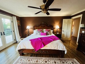 A bedroom with a large bed, two bedside lamps, a ceiling fan, and a view through a glass door. - Magical Farm Villa with Heated Salt Water Pool (Duncan)