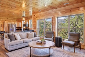 Relax in this spacious living area with a high ceiling, featuring a sofa, armchairs, and a coffee table.