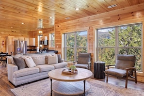 Relax in this spacious living area with a high ceiling, featuring a sofa, armchairs, and a coffee table.