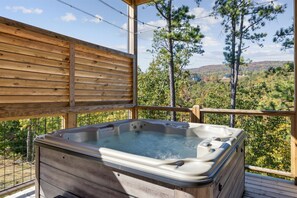 Relax on the elevated deck with a panoramic view of the lush landscape and enjoy a hot tub experience.