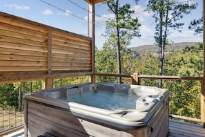 Relax on the elevated deck with a panoramic view of the lush landscape and enjoy a hot tub experience.