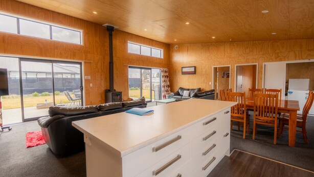 Une cuisine moderne avec un îlot central, des murs en bois et de grandes fenêtres.