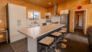 Une cuisine moderne dotée d’un grand îlot central, d’appareils électroménagers en acier inoxydable et de panneaux muraux en bois.