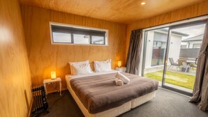 Une chambre avec un grand lit, des murs en bois, une fenêtre et une vue sur l’extérieur.