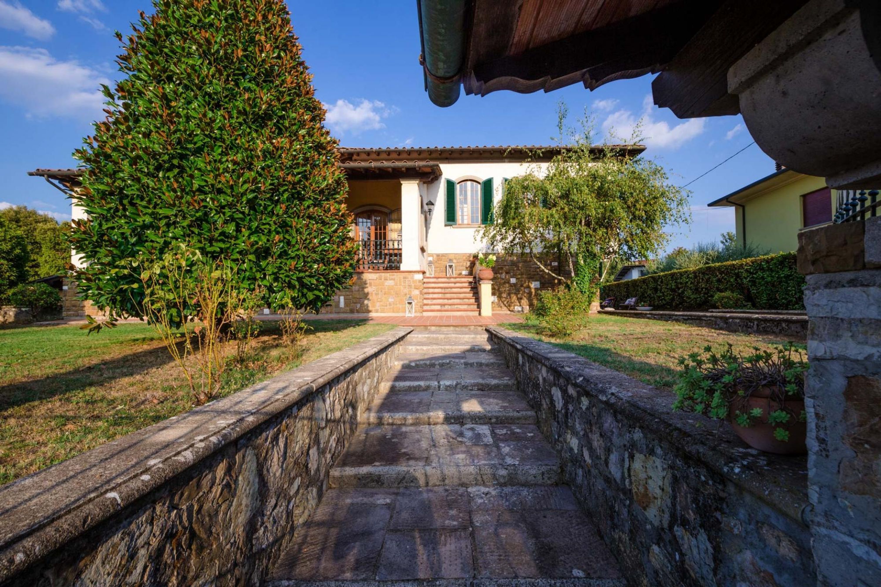 A stone pathway leading to a building with a tiled roof and a small staircase.