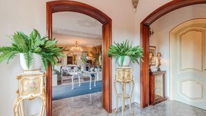 A grand hallway with marble flooring, ornate wooden doors, and large potted ferns. - Villa Cesare Convenient and Smart (Lucca)