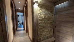 Un pasillo con pared de piedra, puerta de madera y un banco.
