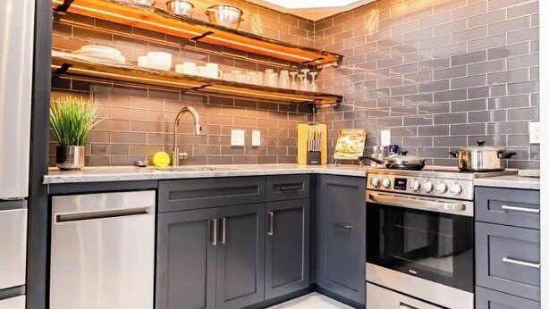 A modern kitchen with dark cabinets, stainless steel appliances, and wooden shelves. - Downtown close to UAB, St. Vincent’s, BJCC and Airport  (Birmingham)