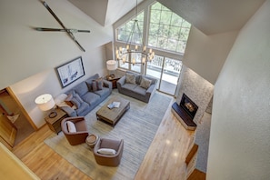 A spacious living room with a large window, a fireplace, and a modern chandelier. - Luxury 4 bedroom Premier Residence at St James Place by RedAwning (Beaver Creek)