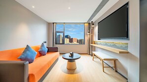 A modern living room with a large window, a sofa, a coffee table, and a flat-screen TV mounted on the wall. - Hilton Garden Inn Chengdu Kuanzhai Alley (Chengdu)