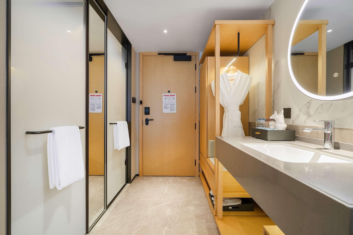 A modern bathroom with a large mirror, a wooden vanity, and a towel rack.