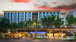 A modern hotel with multiple floors, a prominent entrance, and outdoor seating area. - Hilton Garden Inn Chengdu Kuanzhai Alley (Chengdu)